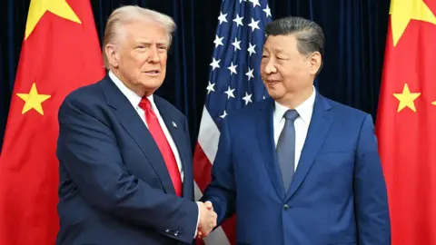US President Donald Trump (L) and China's President Xi Jinping (R) shaking hands in front of US and Chinese flags