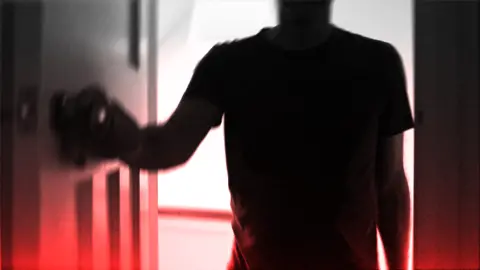A dark silhouette of a person wearing a short-sleeved shirt is positioned in the foreground, facing a door. The person is using their left hand to grasp and turn a doorknob. The background is brightly illuminated, casting the figure into deep shadow and creating a high-contrast effect. A red gradient overlays the bottom portion of the image, contributing to an eerie or dramatic atmosphere