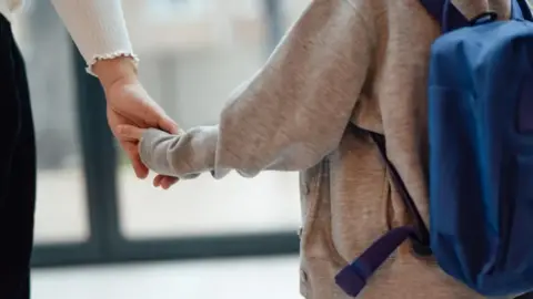 A stock image of a child holding an adult's hand.