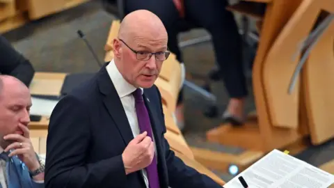 Getty Images John Swinney speaking at Holyrood