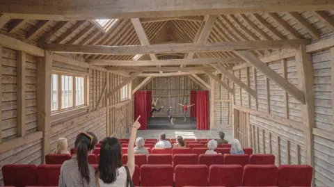 Simon Knight Architects An artist's impression of the theatre barn. There are about seven rows of red seats, a grey floor space and a small stage with red curtains. The sides of the barn are all wooden planks with a V-shaped ceiling.
