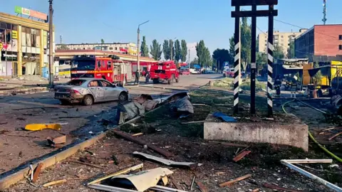 Damaged buildings and a car seen in Dobropillia in Ukraine's eastern Donetsk region