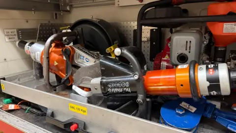 Hydraulic cutting equipment in a locker on the side of a fire engine.