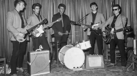 Pete Best The original five piece line-up of The Beatles with 50s style haircuts in light jackets with black shirts and trousers