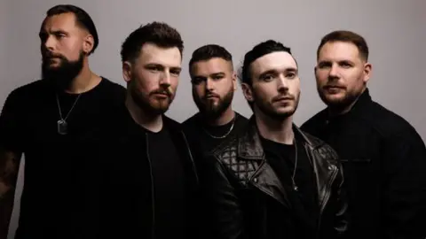 A promotional picture of band Defect, with five men dressed in black looking at the camera