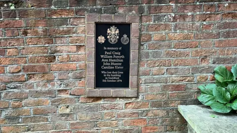 Adrian Harms/ BBC A bronze plaque commemorating those who died is set into the wall of Quakers acre on North Street in Guildford