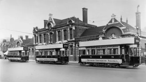 Brighton Tram 53 Society Black and white image of three trams parked on a roadside in front of a large brick building