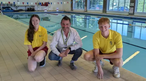 Lewes District Council Three people squatting by a swimming pool. 