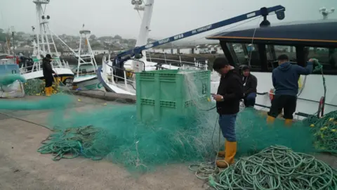 Fishermen working on nets on the harbour side. 