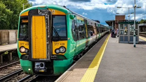Getty Images A Green Southern train arriving at a station, with people waiting to board.