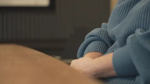 hands and arms of the victim in a blue jumper. Anonymous shot