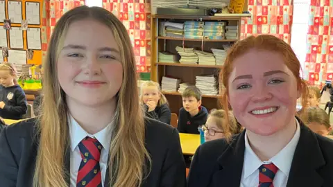 Students smiling into the camera in a classroom setting