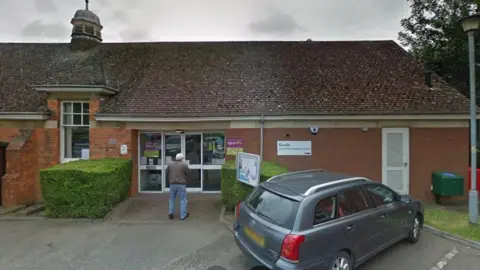 Google Single-storey section of brick-built library building with small cupola on roof and "library plus" sign by door