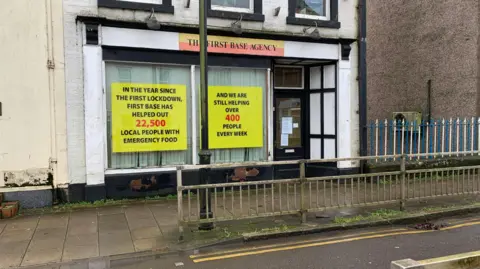 Another view of the First Base Agency from the front with railings in front and two large windows