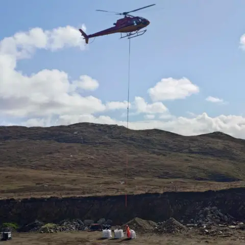 HES A helicopter being attached to bags of construction material