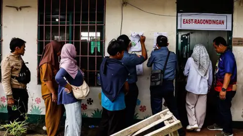 Getty Images Villagers stand in a queue and look for their name as they cast their vote at the school precinct during the 2025 midterm elections on May 12, 2025