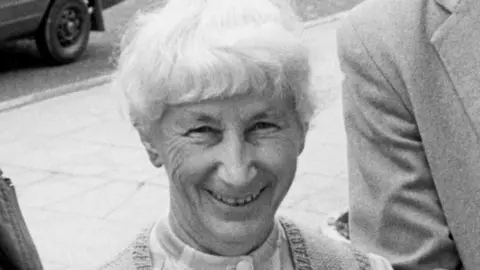 Supplied A black and white picture of Mary Wairing. She has short white hair and is smiling at the camera.