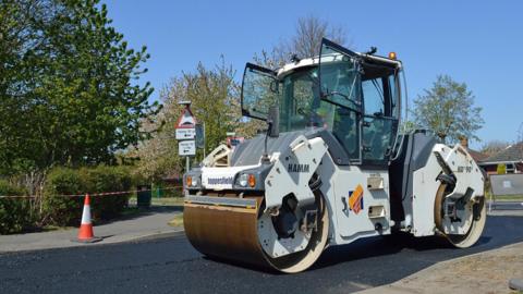 A roller applying tarmac to a road