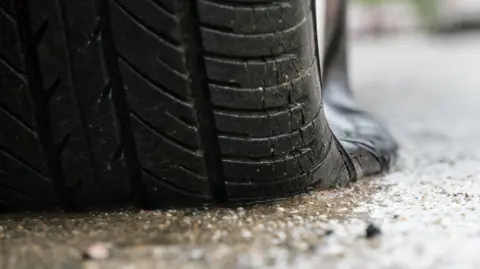 A flat tyre sat on a wet concrete road