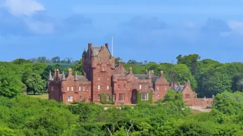Anne Burgess Ayton Castle with a number of turrets and towers stands in a landscape of trees