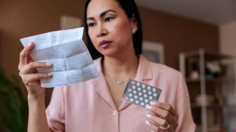Getty Images A woman holding HRT tablets