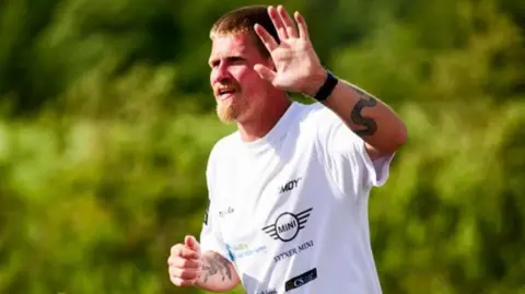 Finn Colin Laurence Denis waving while running.