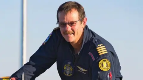 A smiling James O'Connell is seen in his blue and yellow uniform as he prepares for take off