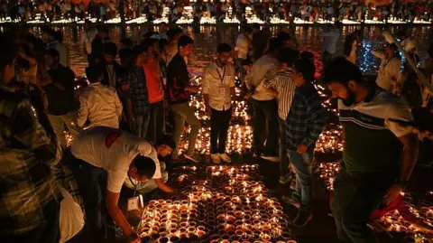 Getty Images People light earthen lamps on the banks of the Sarayu River in Ayodhya on November 11, 2023