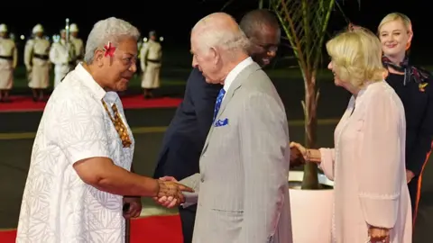 Getty Images Britain's King Charles and Queen Camilla are greeted by Samoa's Prime Minister Fiame Naomi Mata'afa as they arrive at Faleolo International Airport in Samoa