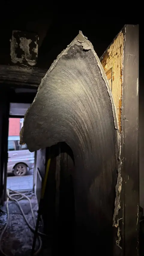 Leicestershire Fire and Rescue Service Interior shot of a fire-damaged building with charred walls and remnants of a doorway. 