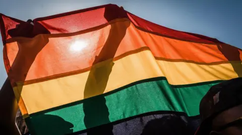 People holding a rainbow Pride flag.