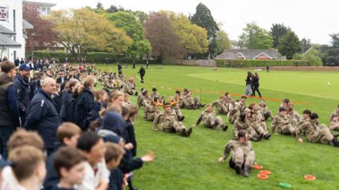 Pupils and staff from Exeter School shuffle along a school field on their bottoms for a special charity fundraiser