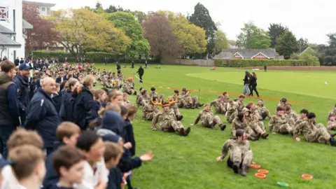 Pupils and staff from Exeter School shuffle along a school field on their bottoms for a special charity fundraiser