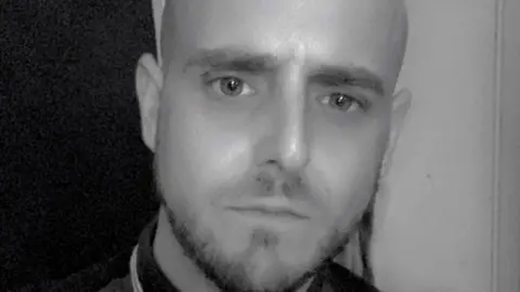 Facebook Matthew Waddell: a man with a small moustache and beard looking intently into the camera. 