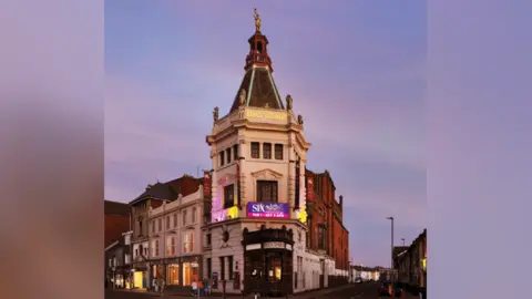 A CGI image of how the front of the theatre would look, with new lighting. The theatre is pictured at dusk.