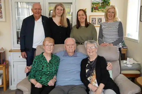 Gladys, front left, sitting on a sofa and surrounded by family