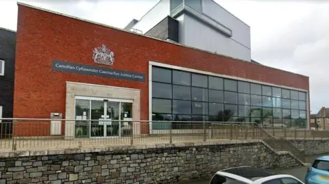 The exterior of Caernarfon Crown Court - a modern red brick building with large windows.