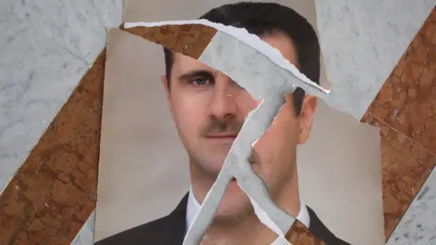 Getty Images  A torn portrait of Bashar al-Assad, that appears to have been arranged, is seen inside the Presidential Palace on December 10, 2024 in Damascus, Syria. 