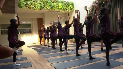 En yoga los estudiantes posan sobre esteras de yoga.