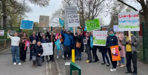 Several teachers striking with pickets outside a school