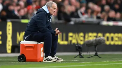 Uruguay head coach Marcelo Bielsa watches while sitting on a upturned cool box