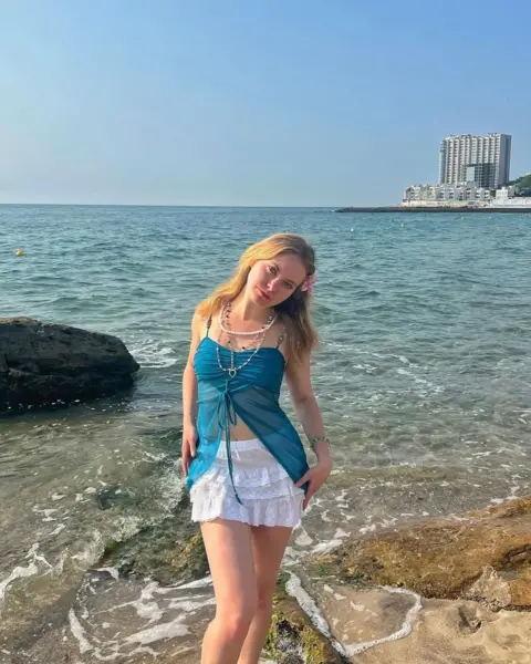 Alena Somova Anastasiia is standing in the middle of the shot on the shore of Odesa Black Sea. With the sea behind her.