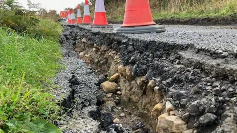 Phil Bodmer/ BBC The damaged landslip-hit road, with parts crumbled away