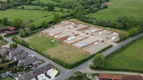A drone image of an alleged unauthorised traveller development on the northern edge of Willows Green. A hole has been cut in a fence to allow access to an area which has been covered in hardcore. Several fences have been erected, dividing the field into plots.