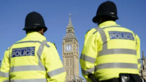 Part of the Palace of Westminster is seen between two Metropolitan Police officers in Parliament Square, London. 