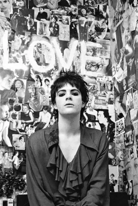 Valerie Phillips Richey Edwards stands in front of an intricate photo montage