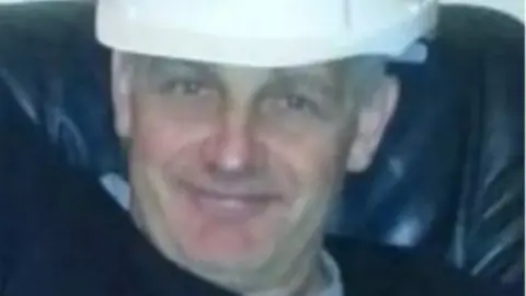 Igor Malka wearing a white hardhat. He is smiling and sitting on a leather chair