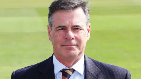 Jason Gallian poses in a suit and tie at an Essex Cricket photocall.