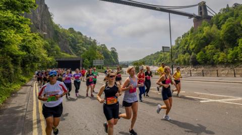 Runners running under the Clifton Suspension Bridge in Bristol 