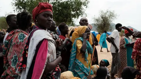 Women stand in a line to receive aid.